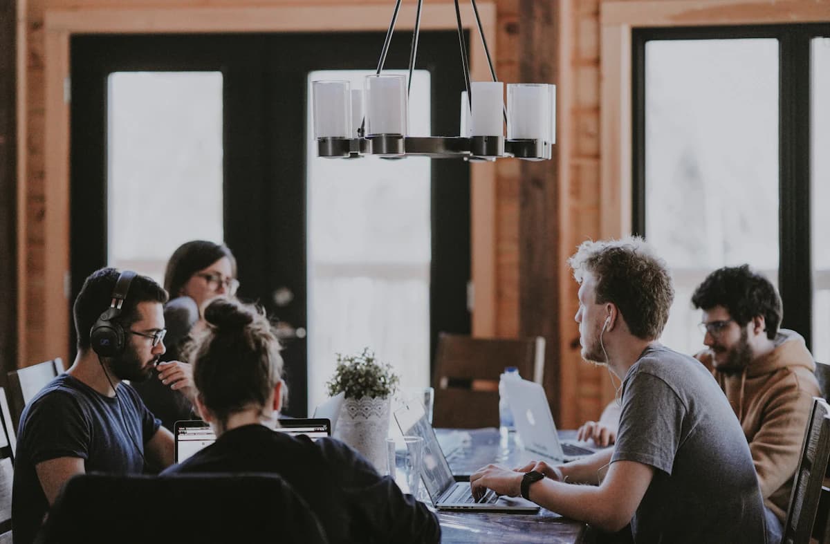 A team in a meeting around a table with laptops open